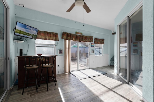 dining room featuring a wainscoted wall, ceiling fan, and wood finished floors