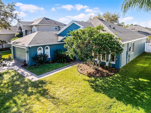 view of front of property with an attached garage, stucco siding, roof with shingles, and a front yard