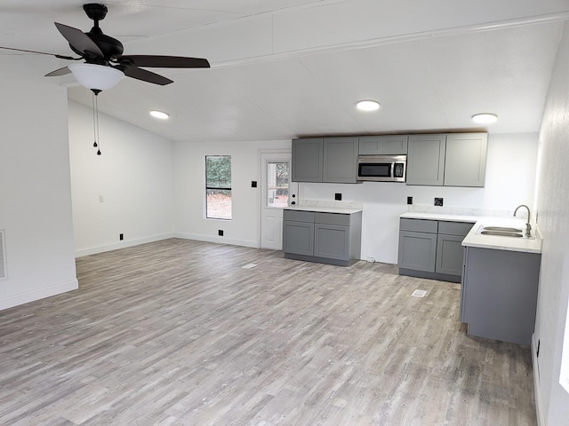 kitchen with lofted ceiling, sink, gray cabinetry, ceiling fan, and light wood-type flooring