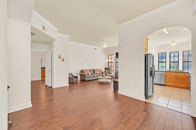 living room featuring crown molding, ceiling fan, sink, and light wood-type flooring