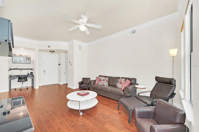 living room featuring hardwood / wood-style flooring, ornamental molding, and ceiling fan