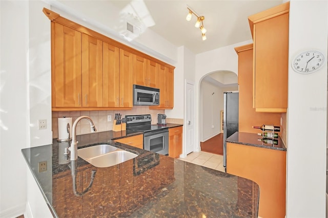 kitchen featuring stainless steel appliances, tasteful backsplash, sink, and dark stone countertops