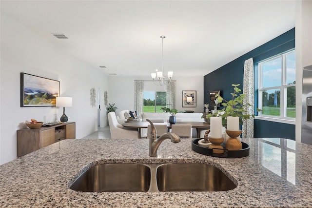 kitchen with light stone counters, sink, and a chandelier