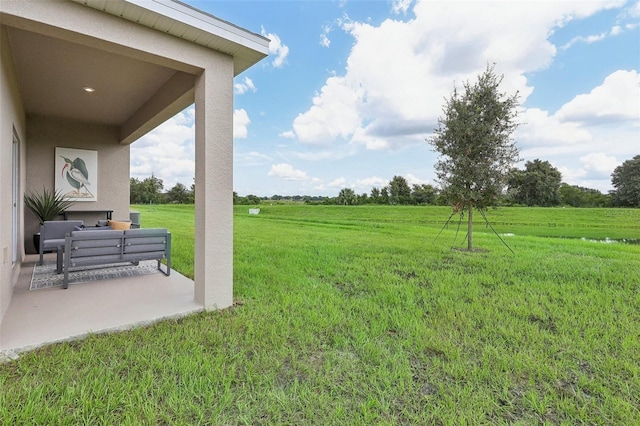 view of yard featuring an outdoor living space, a patio area, and a rural view