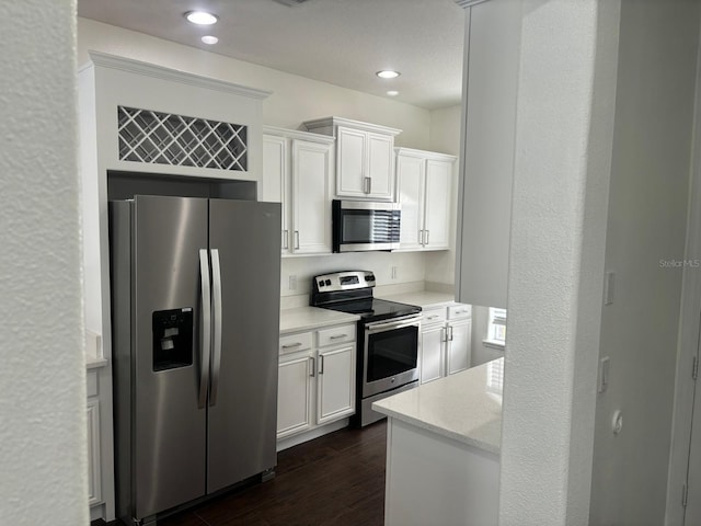 kitchen with white cabinetry, dark hardwood / wood-style floors, appliances with stainless steel finishes, and light stone counters