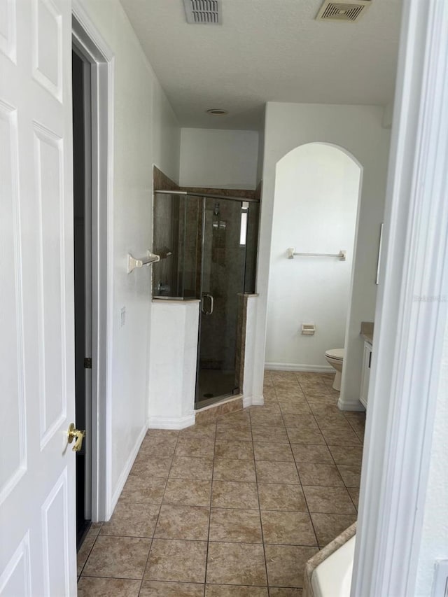 bathroom with a shower with door, toilet, tile patterned floors, and vanity