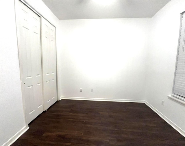 unfurnished bedroom featuring a closet and dark wood-type flooring