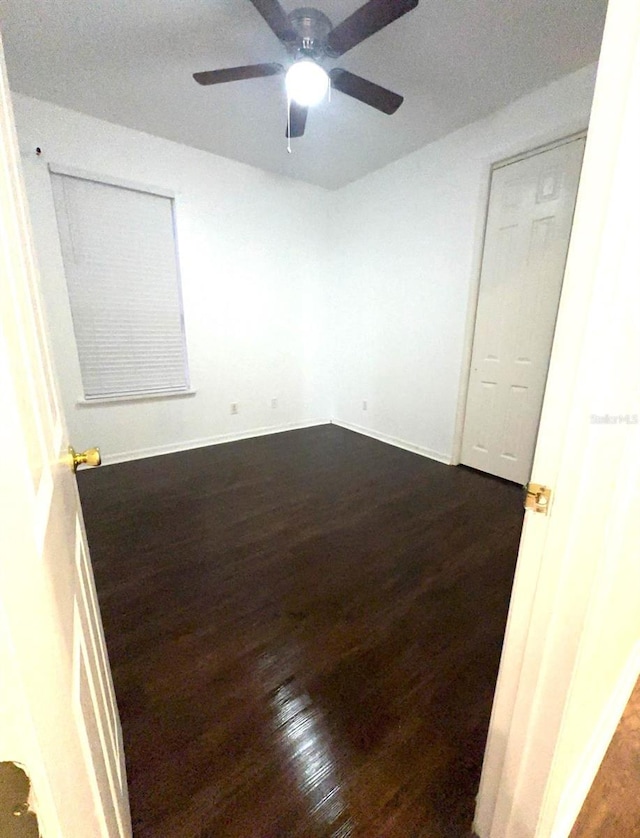 spare room featuring dark wood-type flooring and ceiling fan