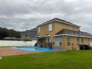 rear view of property with a fenced in pool, a yard, and a patio