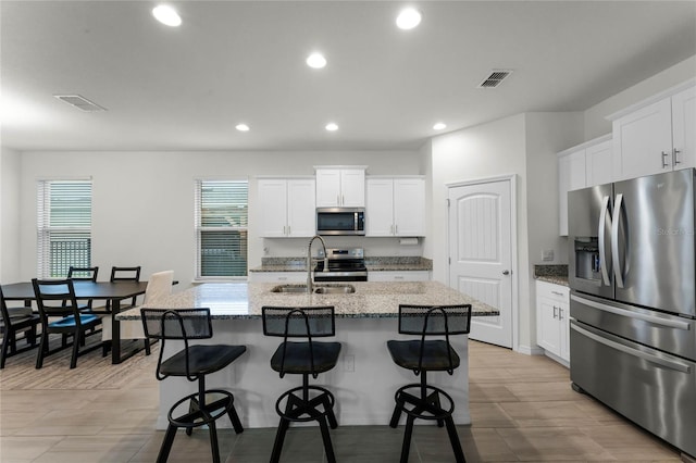 kitchen with sink, white cabinetry, a center island with sink, and stainless steel appliances