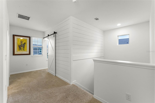 hall featuring light carpet and a barn door