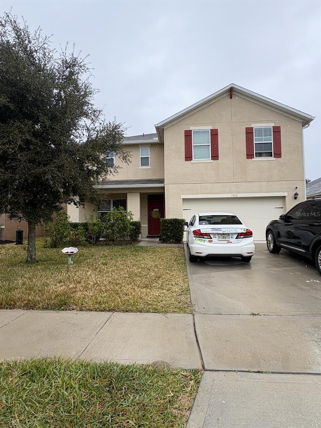 view of property featuring a garage and a front lawn