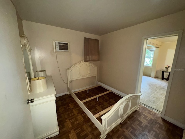 bedroom with dark parquet floors and a wall unit AC