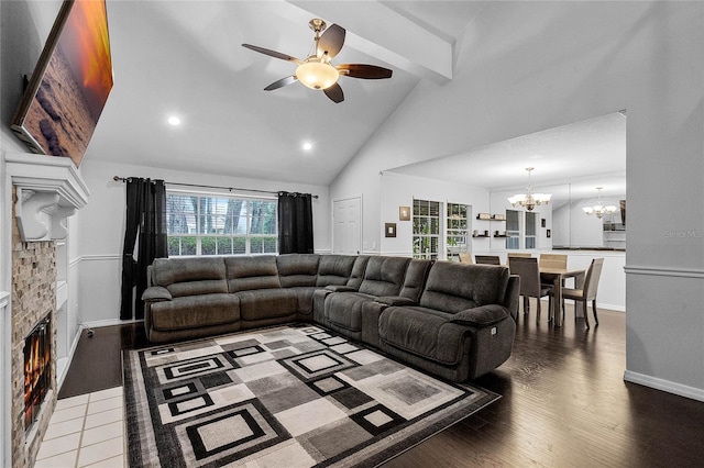 living room featuring hardwood / wood-style flooring, beam ceiling, high vaulted ceiling, a fireplace, and ceiling fan with notable chandelier