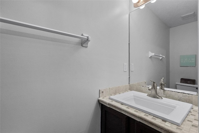 bathroom with vanity, toilet, and a textured ceiling