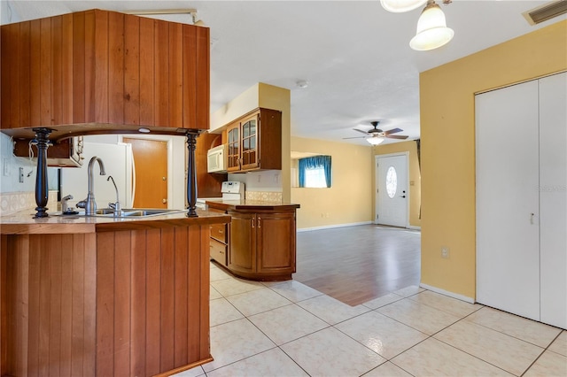 kitchen with sink, white appliances, ceiling fan, light tile patterned flooring, and kitchen peninsula