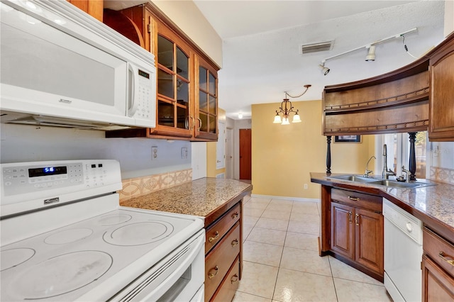 kitchen featuring sink, hanging light fixtures, light tile patterned floors, a notable chandelier, and white appliances