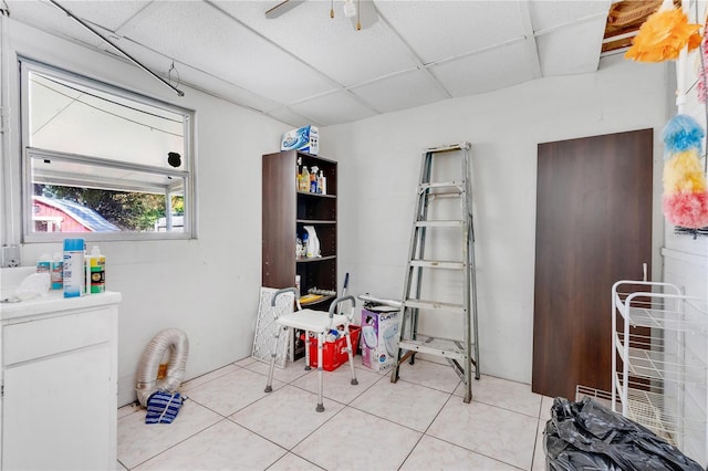 interior space with light tile patterned floors, a paneled ceiling, and ceiling fan