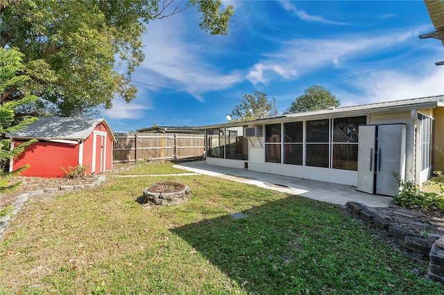 view of yard featuring a storage shed, a fire pit, and a sunroom