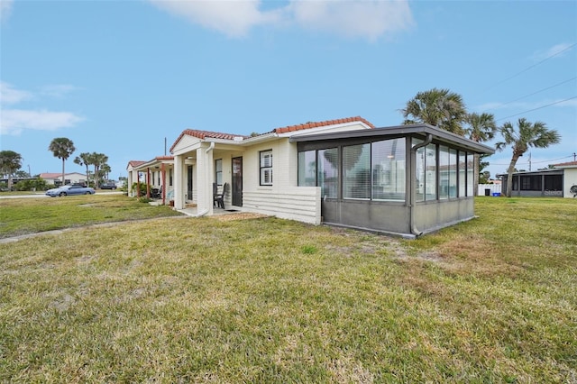 rear view of house with a lawn and a sunroom