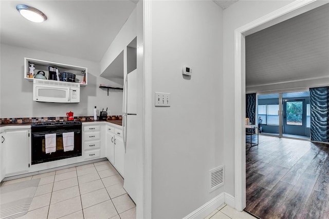 kitchen with light tile patterned floors, white cabinets, and black gas range oven