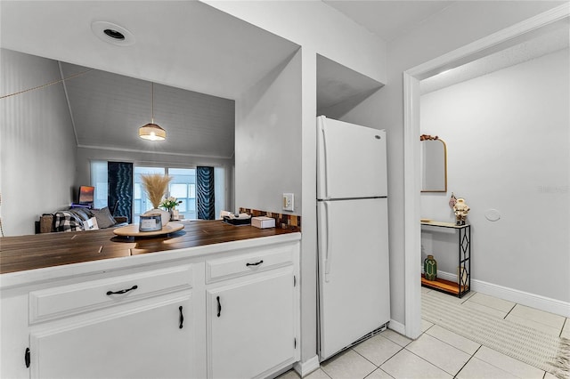 kitchen with decorative light fixtures, white cabinetry, light tile patterned floors, and white fridge