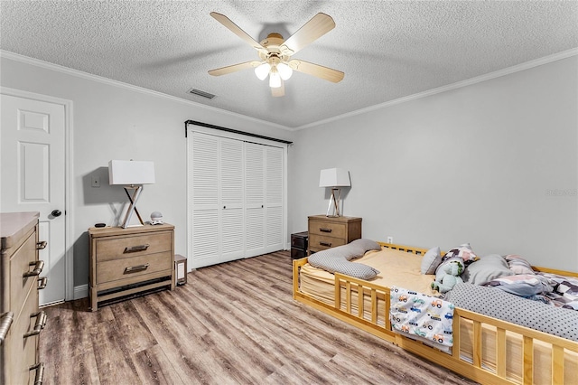 bedroom with crown molding, a textured ceiling, a closet, and ceiling fan