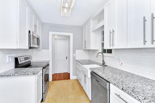 kitchen featuring sink, light stone counters, tasteful backsplash, stainless steel appliances, and white cabinets