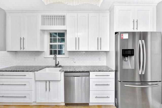 kitchen with sink, appliances with stainless steel finishes, dark stone countertops, tasteful backsplash, and white cabinets