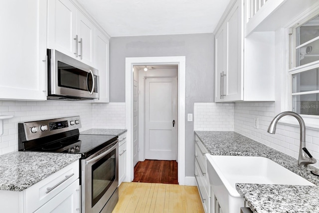 kitchen featuring light stone counters, appliances with stainless steel finishes, sink, and white cabinets