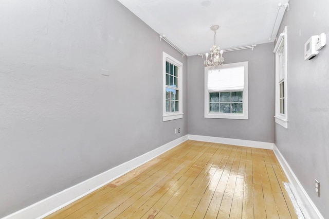 spare room featuring an inviting chandelier and wood-type flooring