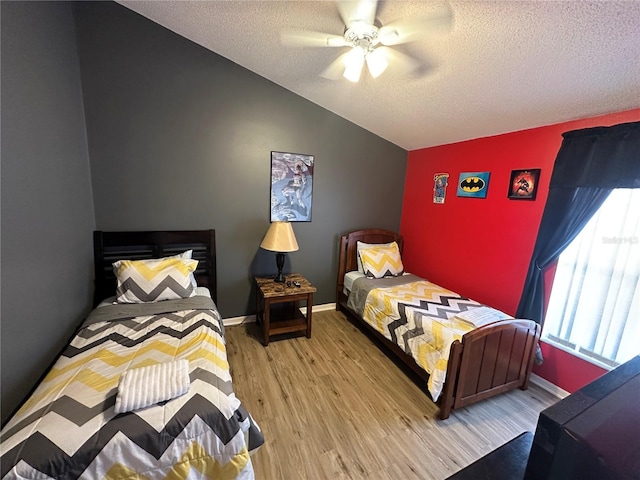 bedroom with light wood-type flooring, ceiling fan, vaulted ceiling, and a textured ceiling