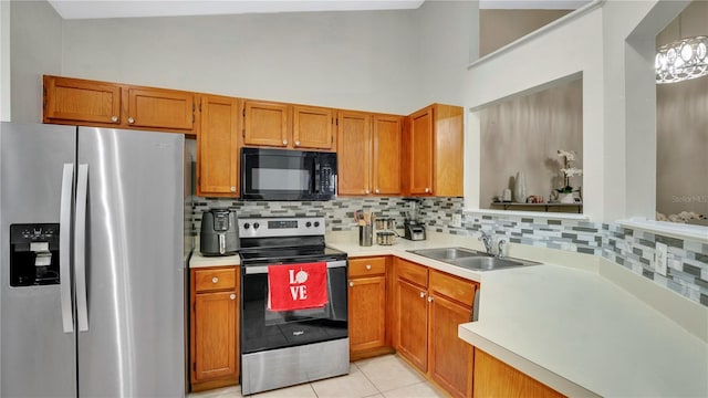 kitchen featuring appliances with stainless steel finishes, light tile patterned floors, decorative backsplash, sink, and pendant lighting