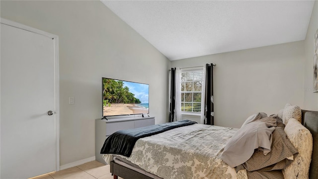 bedroom with vaulted ceiling, light tile patterned floors, and a textured ceiling