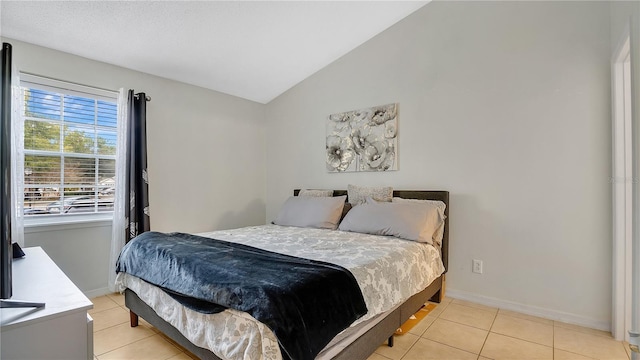 bedroom with light tile patterned floors and vaulted ceiling