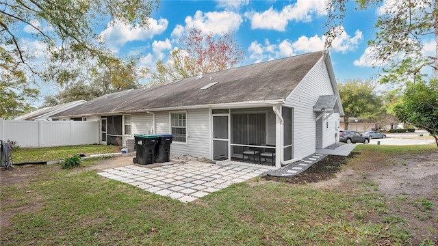 back of property with a sunroom, a patio, and a yard