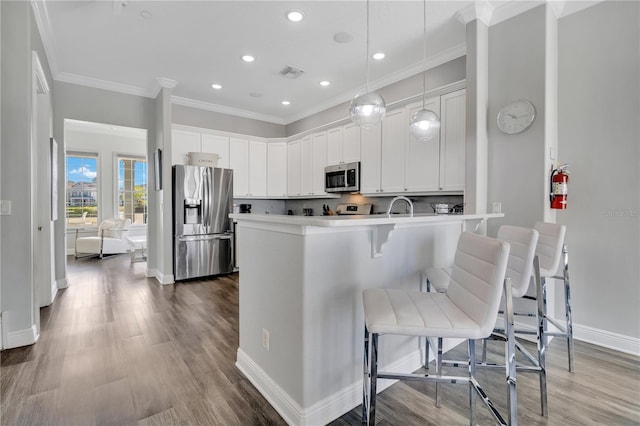 kitchen with decorative light fixtures, white cabinetry, a kitchen bar, kitchen peninsula, and stainless steel appliances