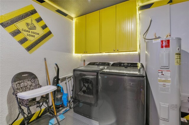 clothes washing area with cabinets, water heater, and washing machine and clothes dryer