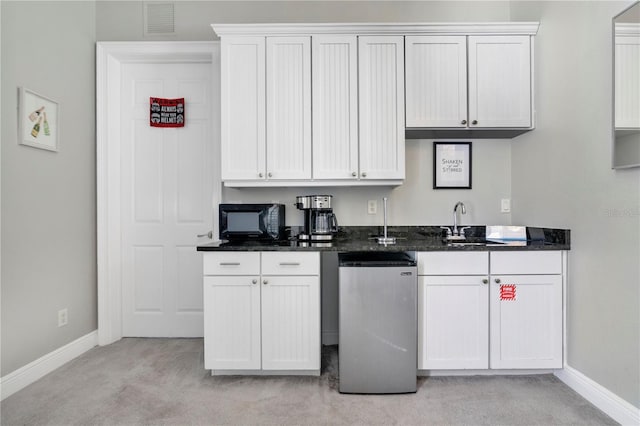 kitchen featuring white cabinetry, sink, light carpet, and stainless steel refrigerator