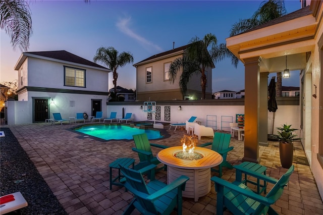 pool at dusk featuring a patio and an outdoor fire pit