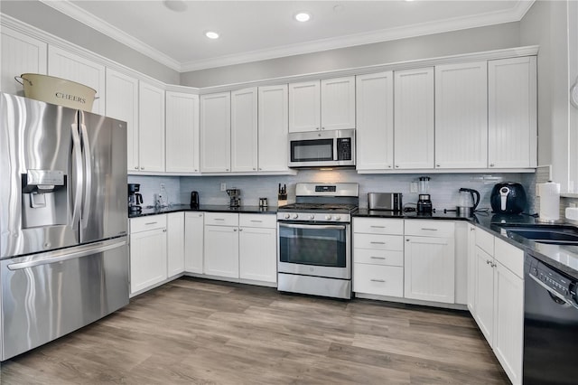 kitchen featuring white cabinets, backsplash, ornamental molding, stainless steel appliances, and light hardwood / wood-style flooring