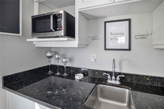 kitchen featuring white cabinetry, sink, and dark stone counters