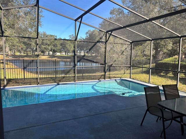 view of pool with a patio, a water view, and glass enclosure