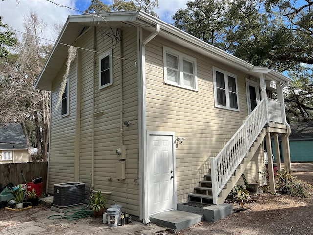 rear view of property featuring stairs, fence, and central air condition unit