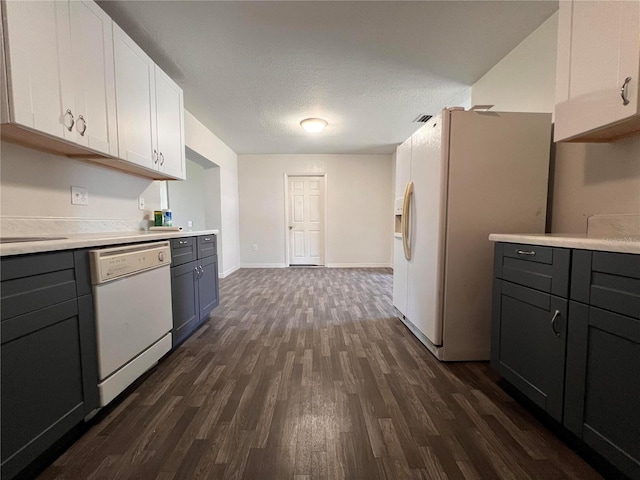 kitchen with a textured ceiling, white appliances, white cabinetry, and dark wood-type flooring