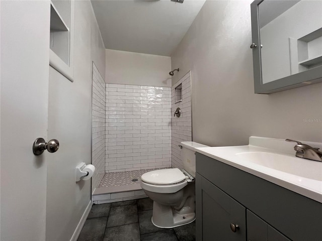 bathroom featuring tiled shower, toilet, and vanity