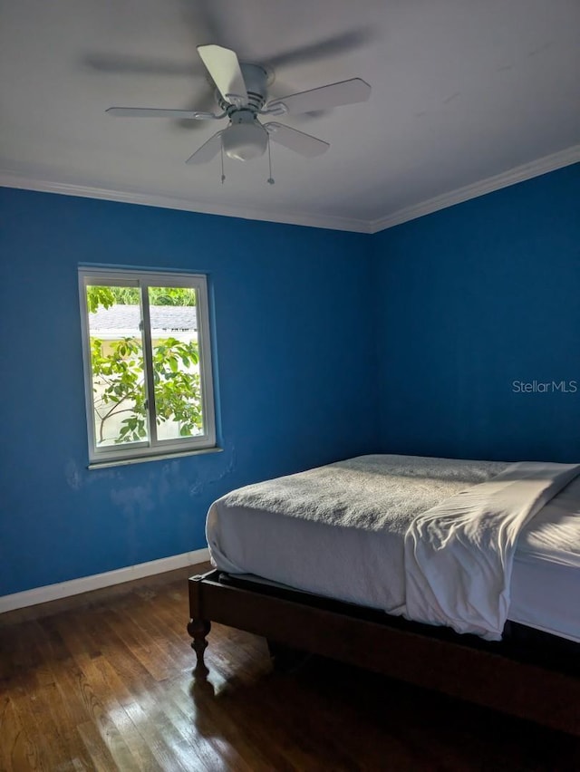 bedroom with hardwood / wood-style flooring, ceiling fan, and ornamental molding