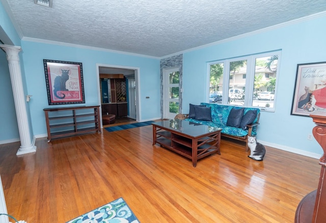 living room with hardwood / wood-style flooring, ornamental molding, and ornate columns