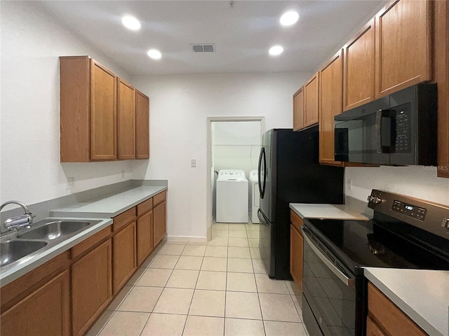 kitchen featuring black appliances, light tile patterned flooring, separate washer and dryer, and sink