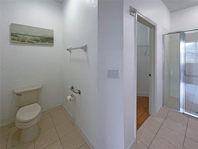 bathroom with toilet, walk in shower, and tile patterned flooring